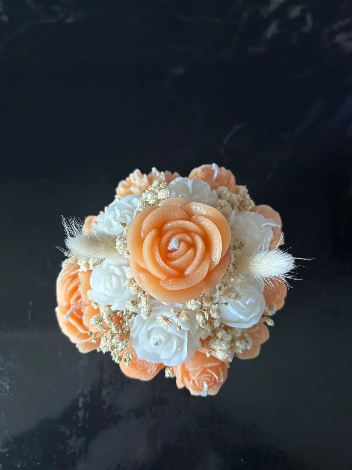 Bouquet de velas em forma de rosas e cravos laranja, pêssego e brancos, com gipsófila e espigas secas, num vaso laranja