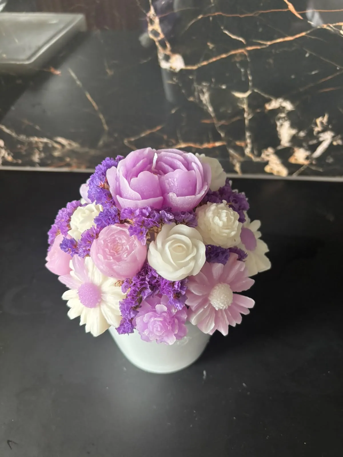 Bouquet de velas com uma peónia lilás, rosas brancas e rosa e margaridas, com flores secas roxas, num vaso branco