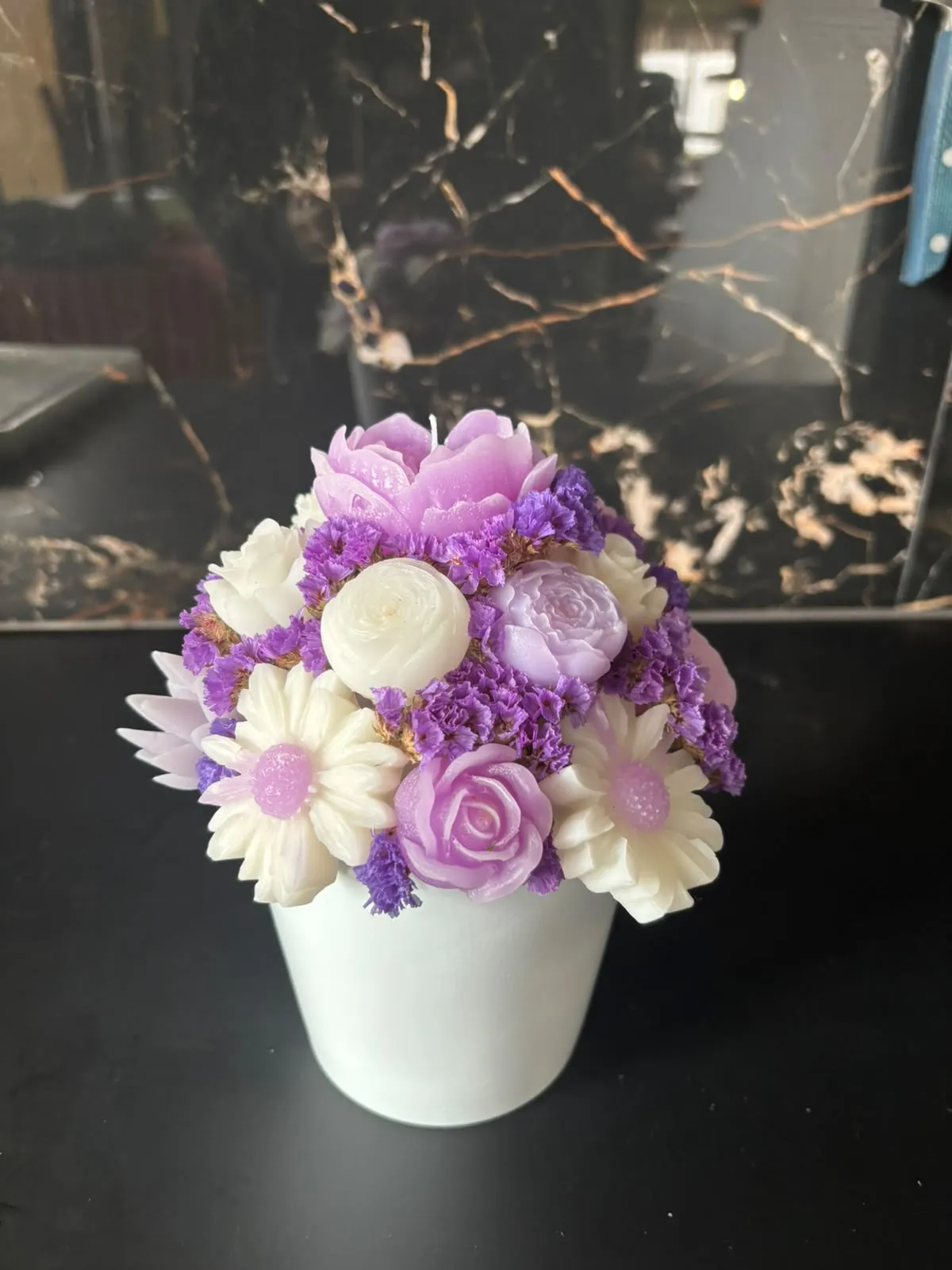 Bouquet de velas com uma peónia lilás, rosas brancas e rosa e margaridas, com flores secas roxas, num vaso branco