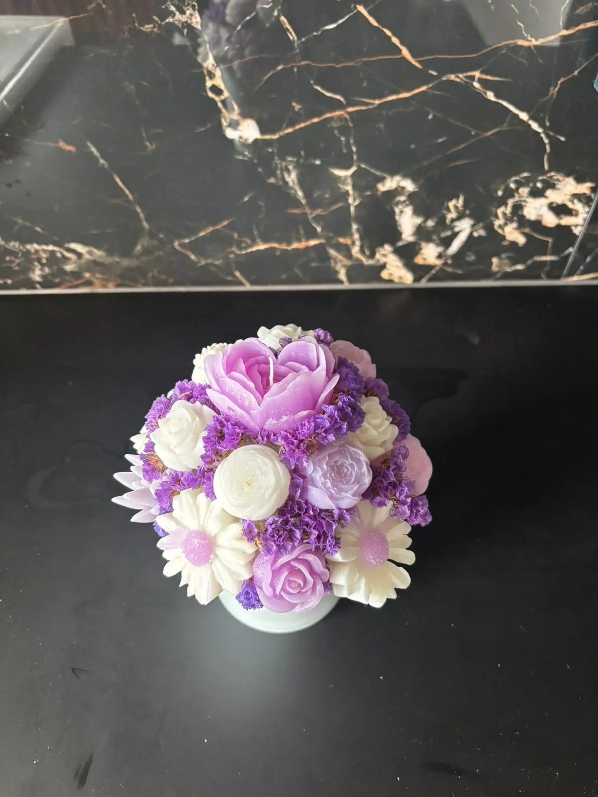 Bouquet de velas com uma peónia lilás, rosas brancas e rosa e margaridas, com flores secas roxas, num vaso branco