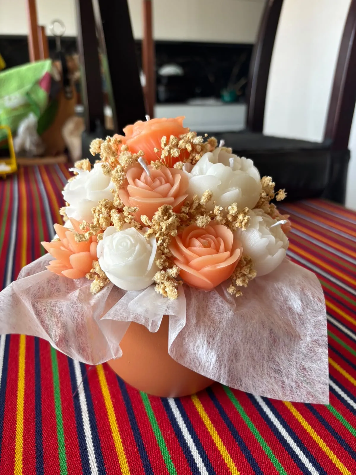 Bouquet de velas em forma de rosas e peónias, em tons pêssego e branco, com gipsófila seca, num vaso de terracota