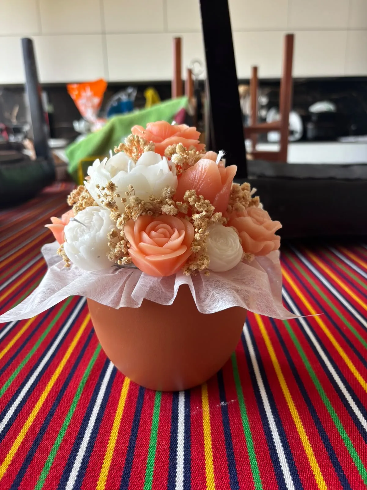 O mesmo bouquet de rosas pêssego e brancas visto de mais longe, sobre uma toalha às riscas