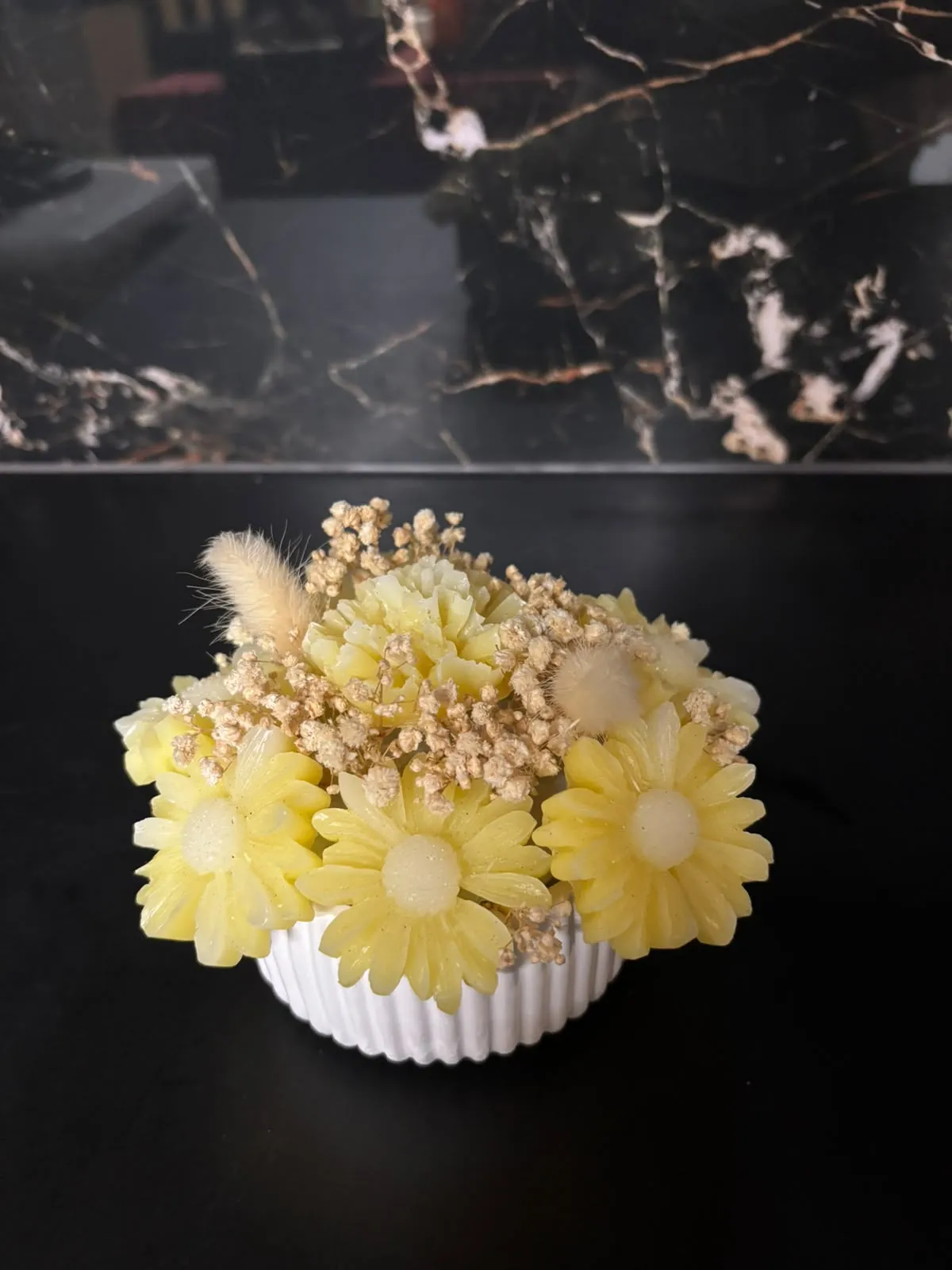 Margaridas em cera, flores secas e plumas decorativas.