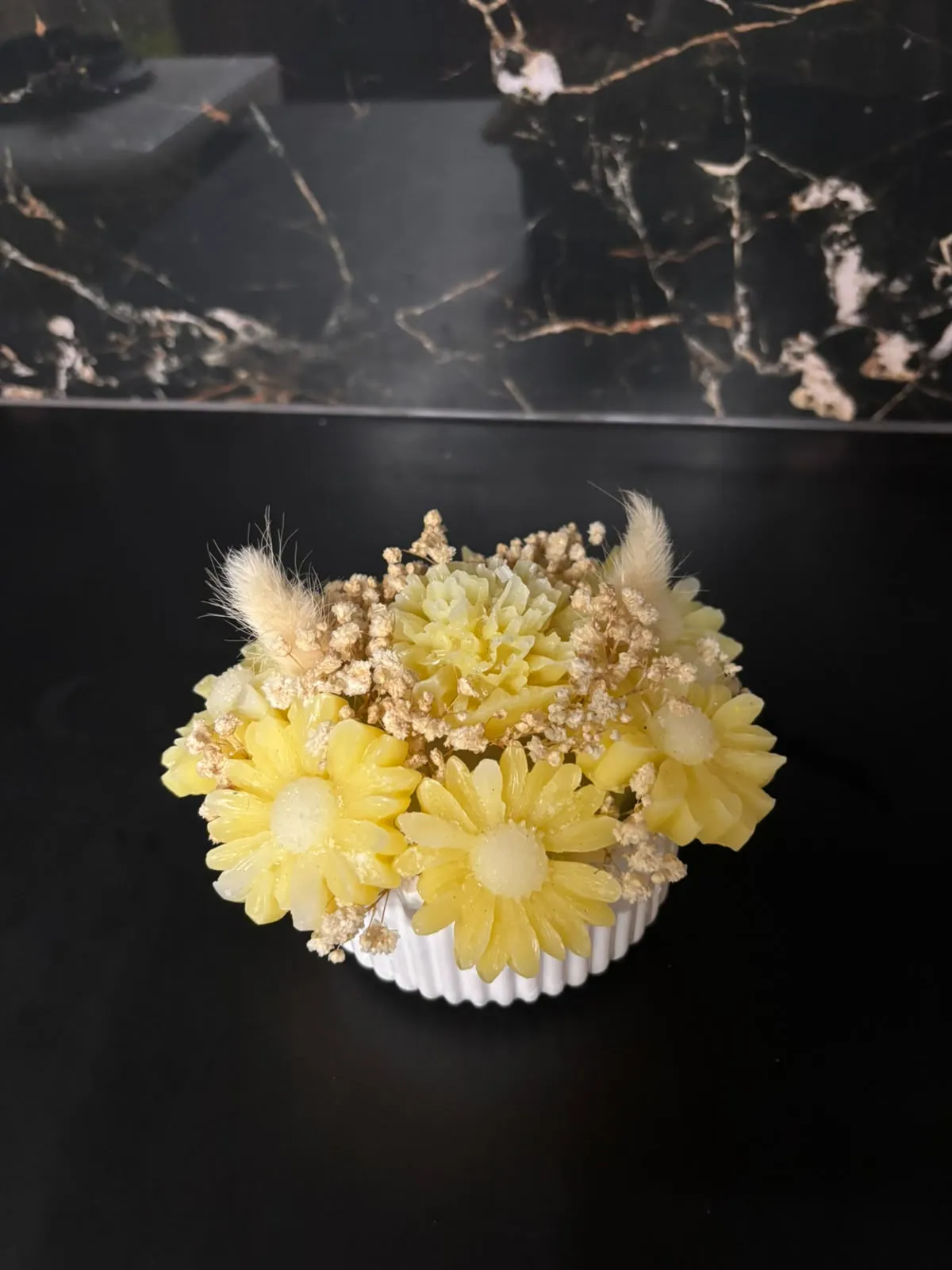 Margaridas em cera, flores secas e plumas decorativas.